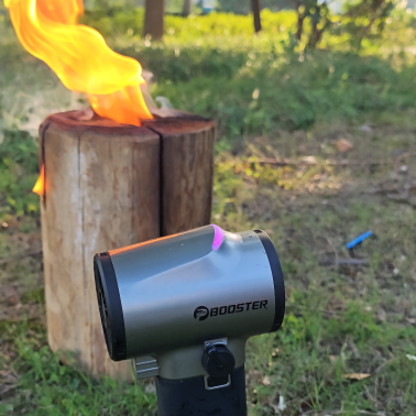 Booster cordless leaf blower assists in outdoor wood fire ignition, with strong wind making the flame burn fiercely, providing efficient support for camping fire starting.