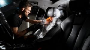 A handsome young man is washing a car.